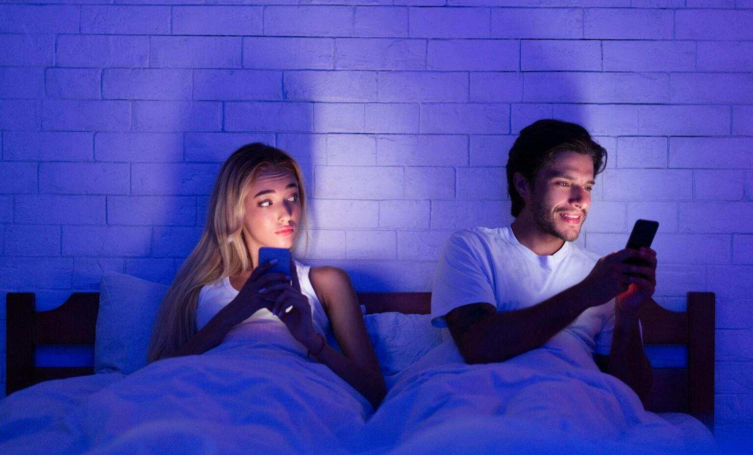 Détecter une infidélité grâce à son smartphone : guide complet Cheating Husband Chatting On Cellphone Lying With Wife In Bed