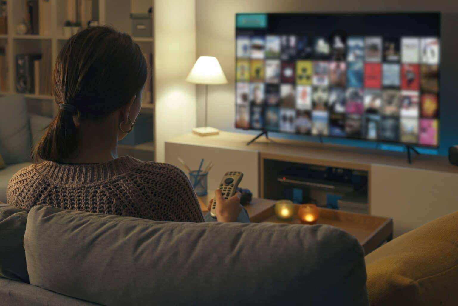 Comment bien choisir son téléviseur : le guide Woman watching TV at home and relaxing