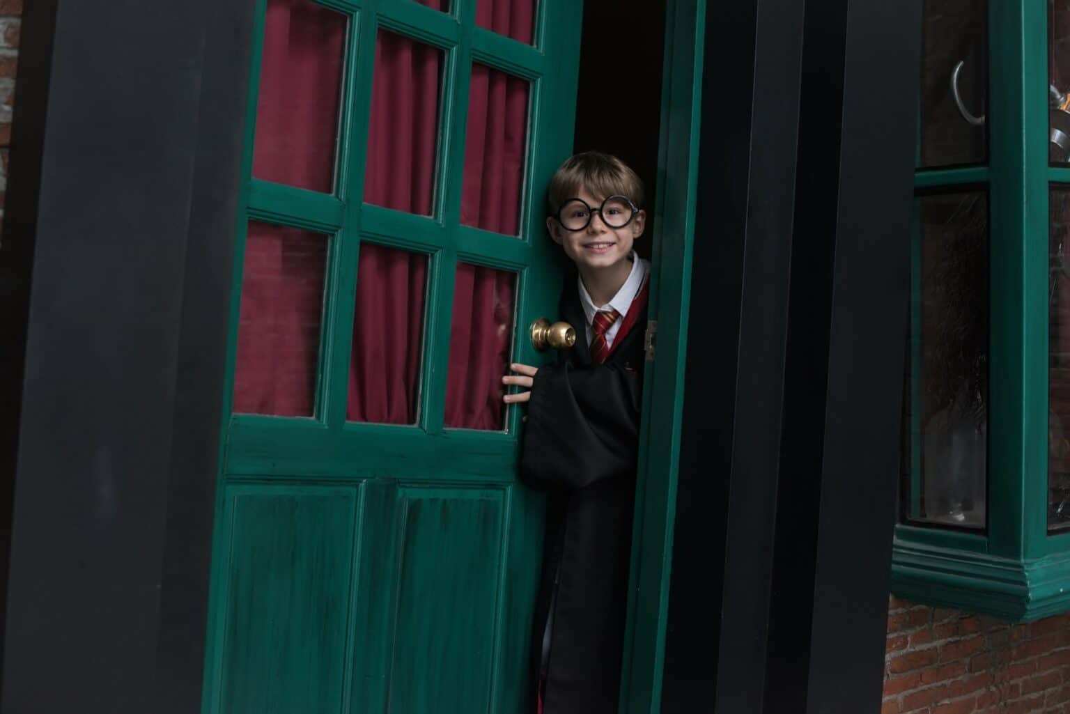 Boy in Harry Potter costume standing behind door
