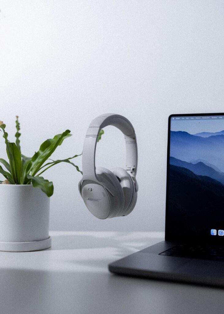 a laptop computer sitting on top of a desk next to a plant