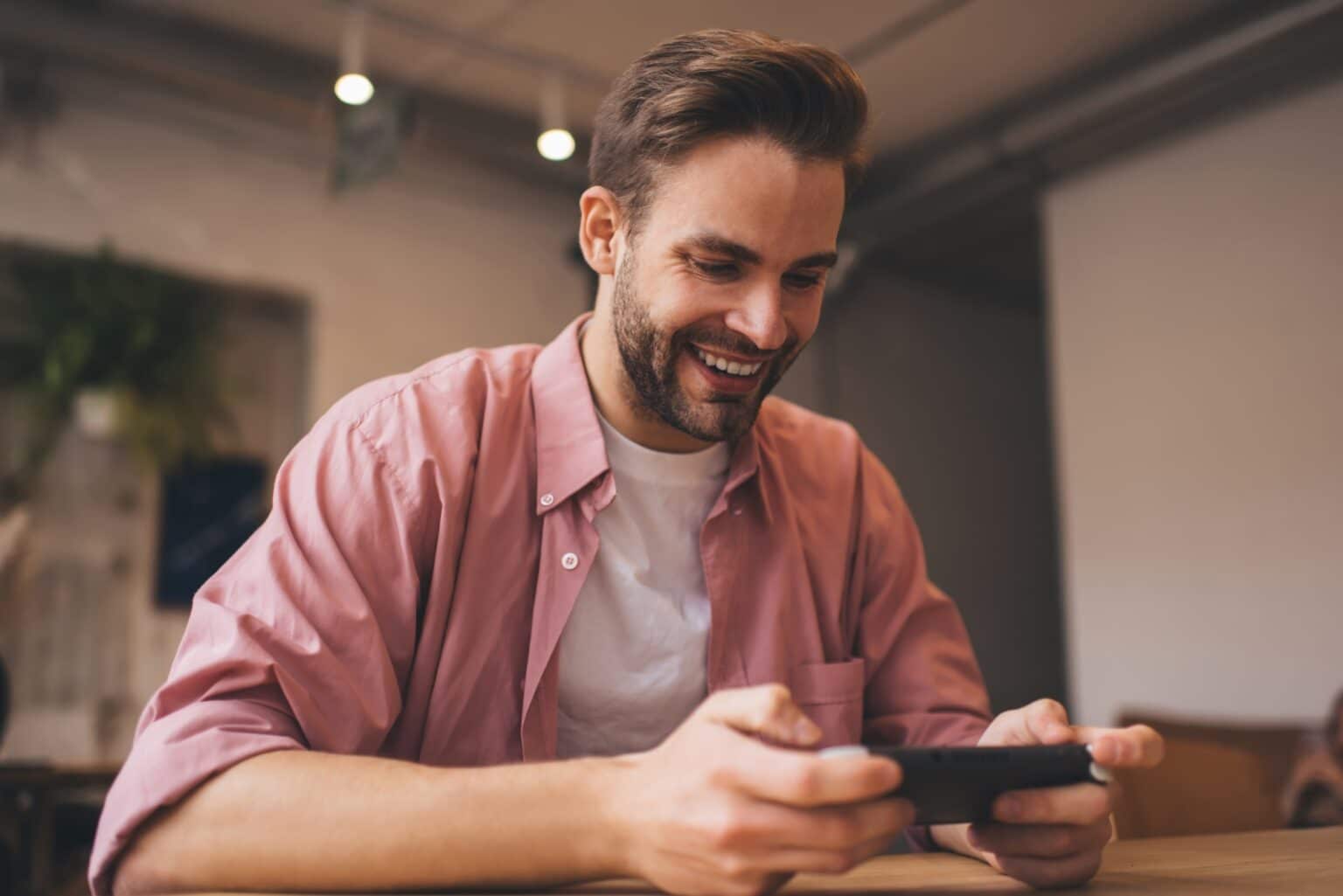 Cheerful hipster guy enjoying time for playing virtual 3d via nintendo console joystick while waitin
