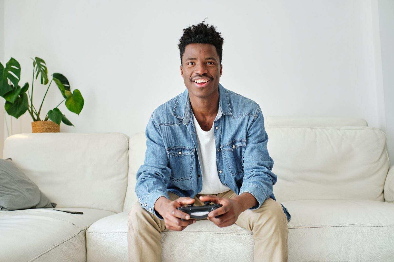 Happy black man with game pad playing on sofa