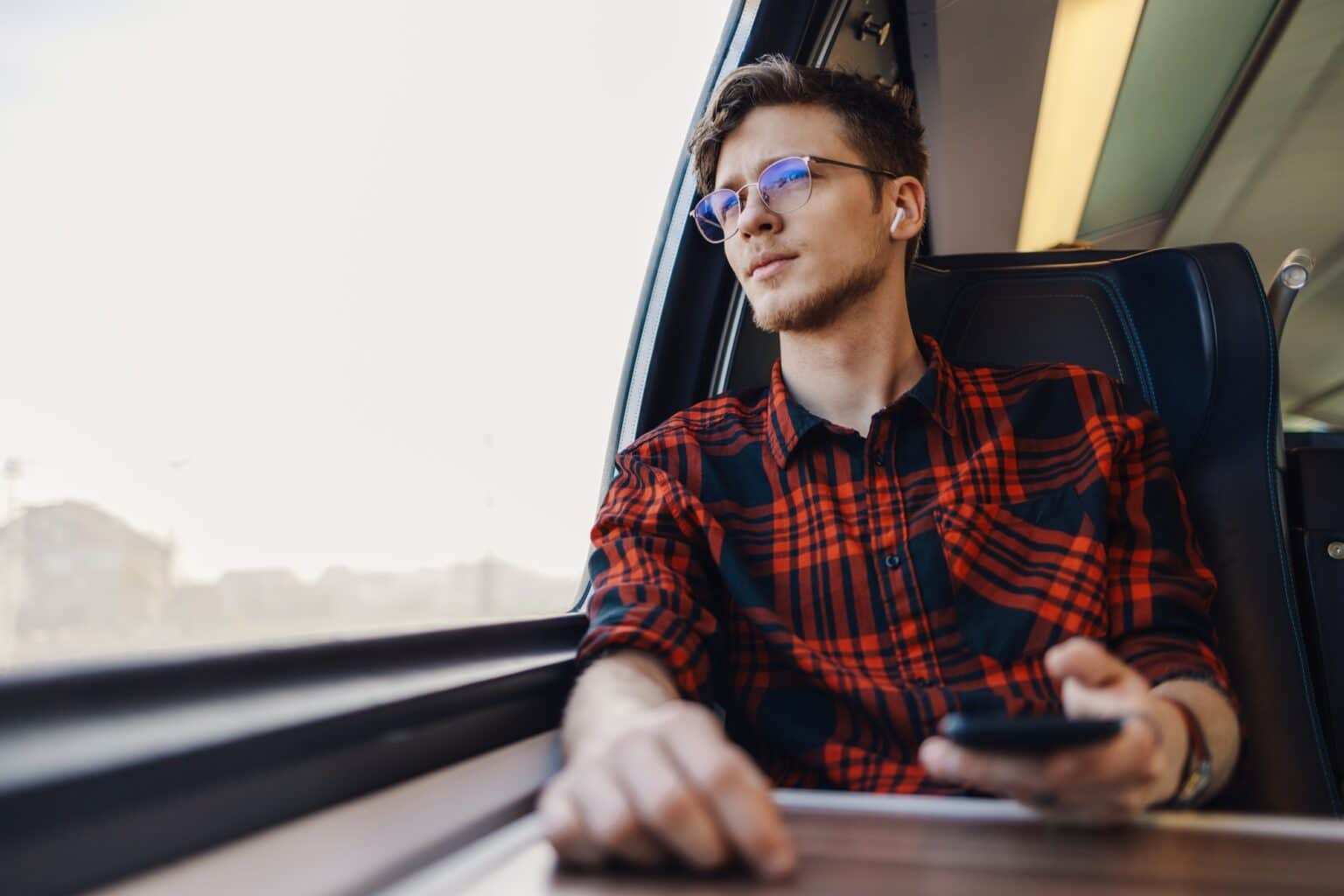 A passenger in train is listening music and looking trough train window