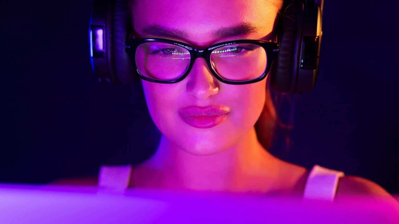 Woman Playing Game on Laptop With Glasses and Headphones