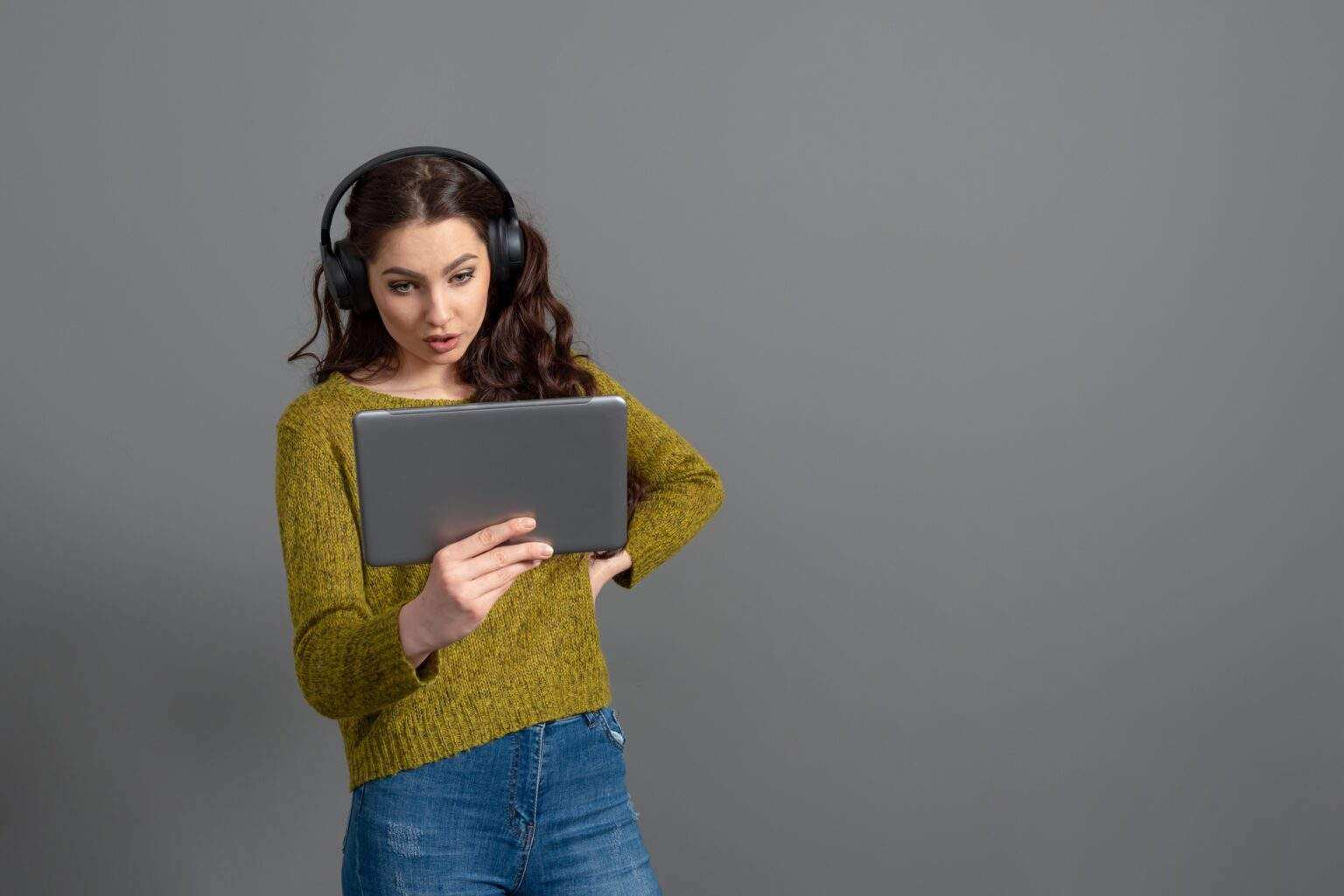 young woman with headset and tablet in hand playing games and talking to friends online