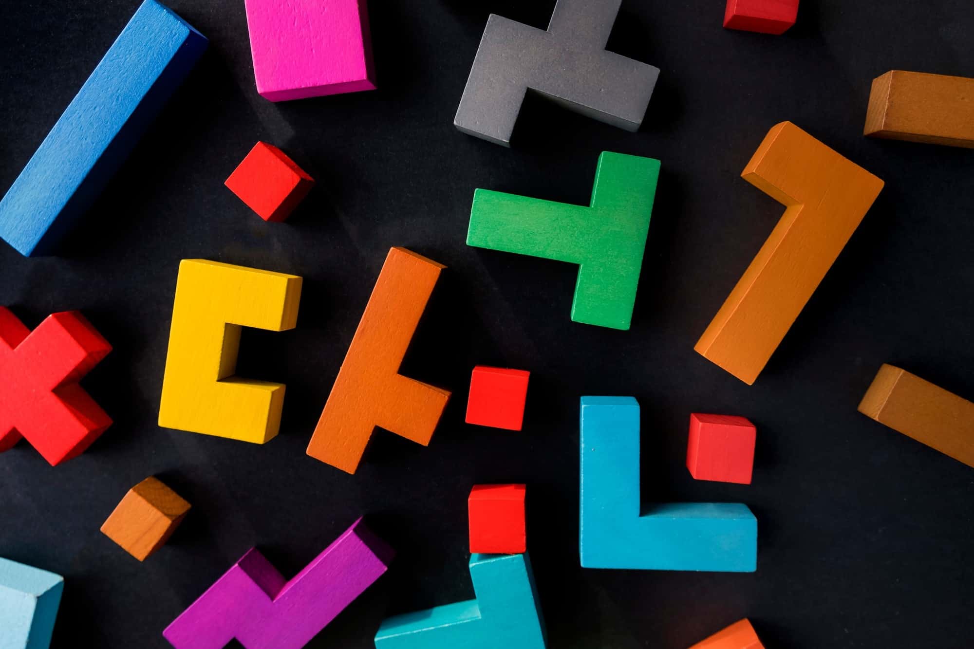 Different colorful shapes wooden blocks on black background, flat lay.