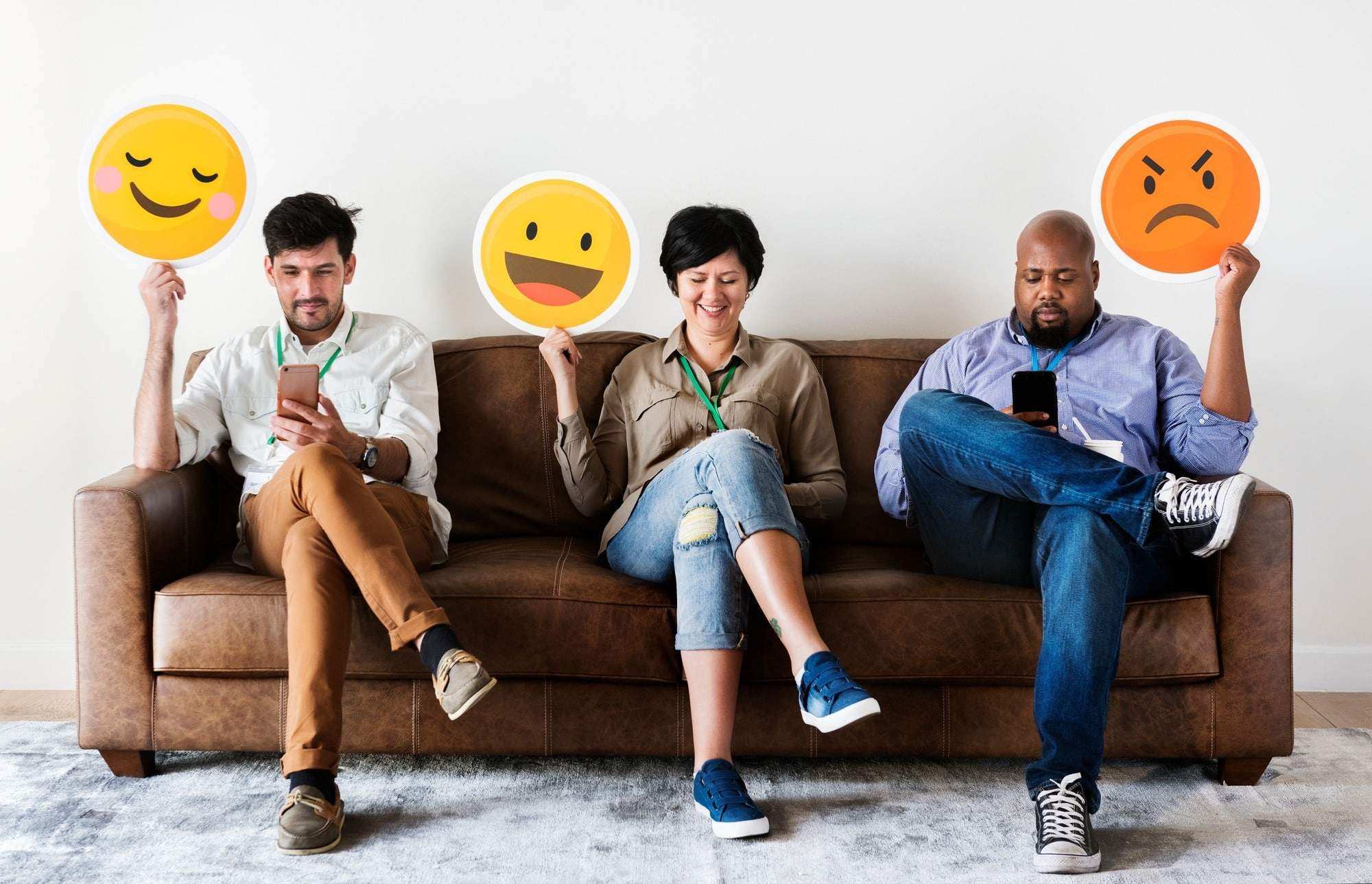 Diverse people sitting and holding emojis logos