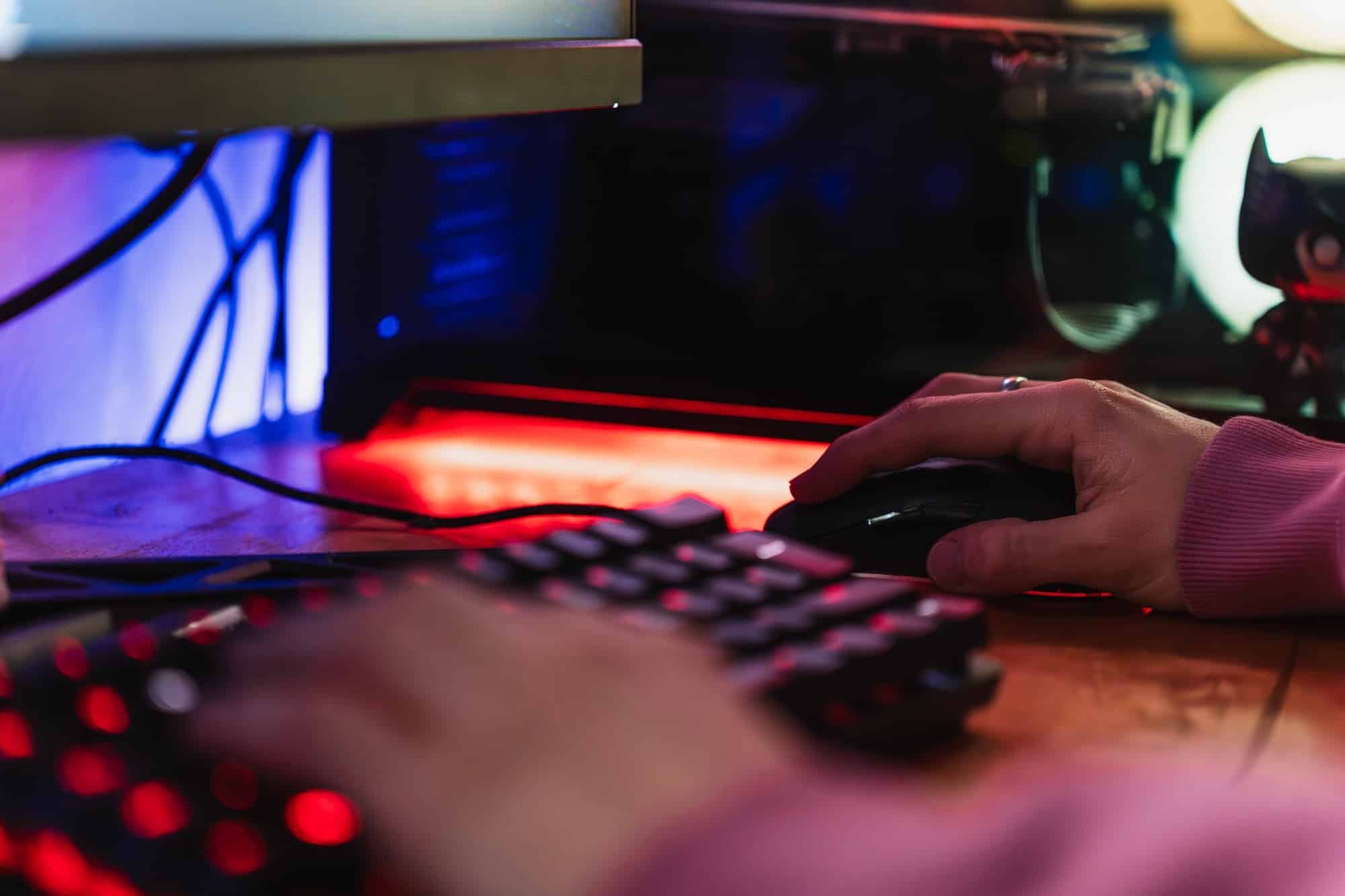 Hands of a gamer playing videogames with his LED keyboard and mouse in his gaming setup