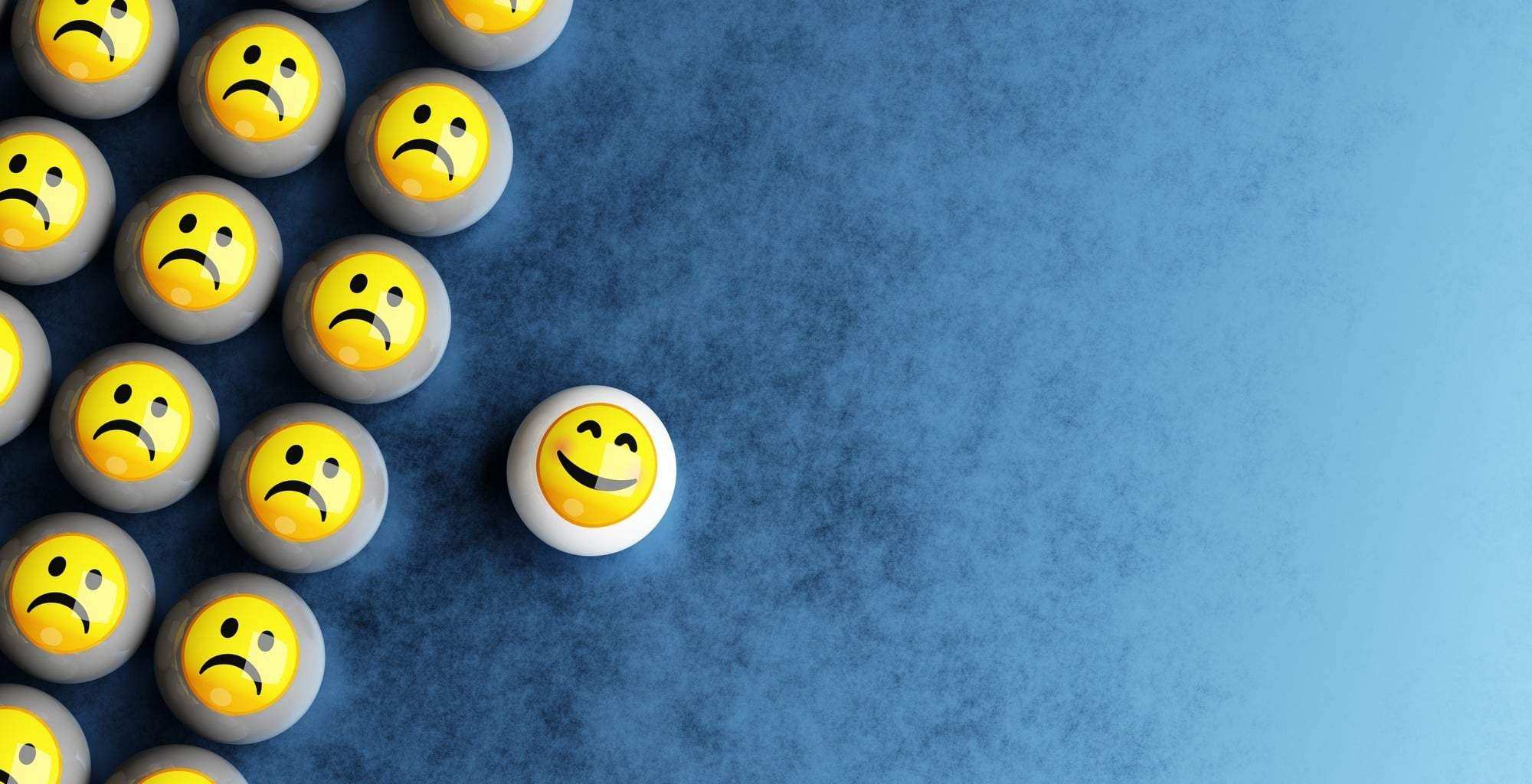 Happy smiley emoji face among sad emoticon faces