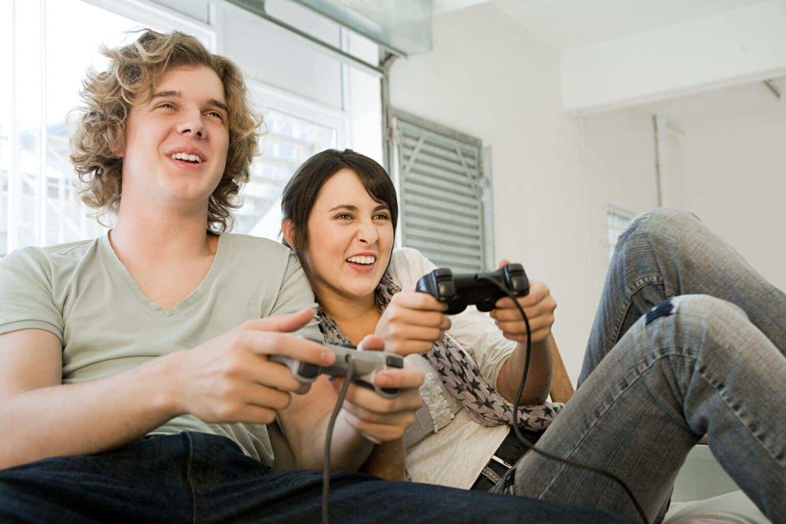 Teenage couple playing with games consoles