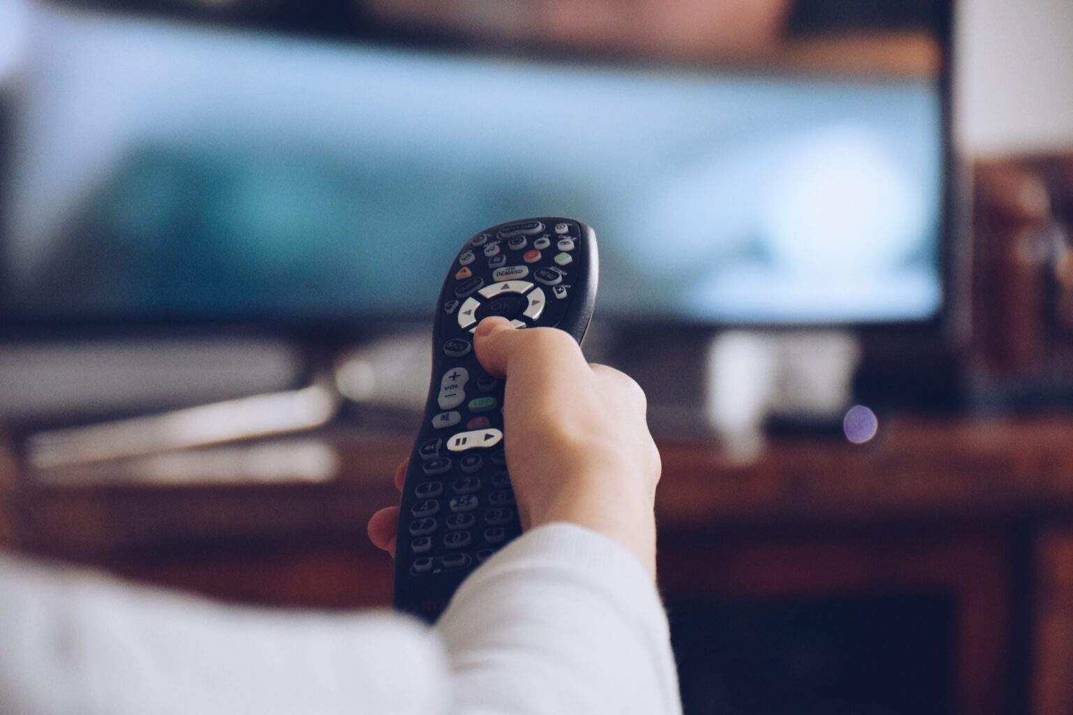 Young girl holding a remote to flip channels on a TV