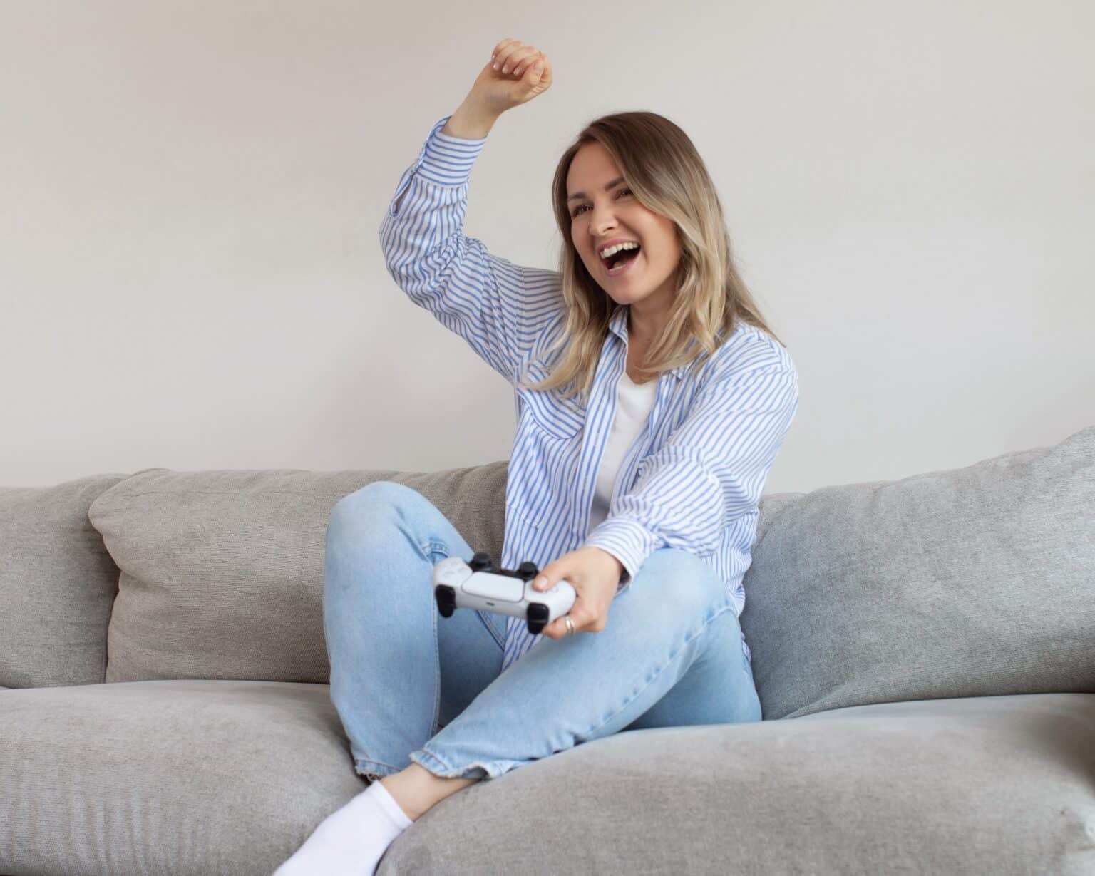 Excited young woman plays videogame in living room