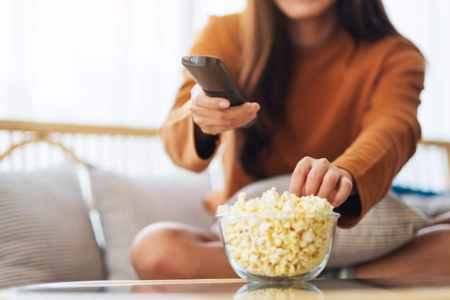 Validé saison 4 : date de sortie, épisodes, casting et trailer a young woman eating popcorn and searching channel with remote control to watch tv
