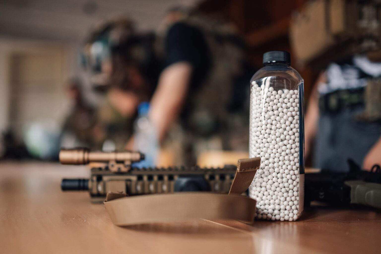 Close up of bottle full of ammo and plastic bullets on table.