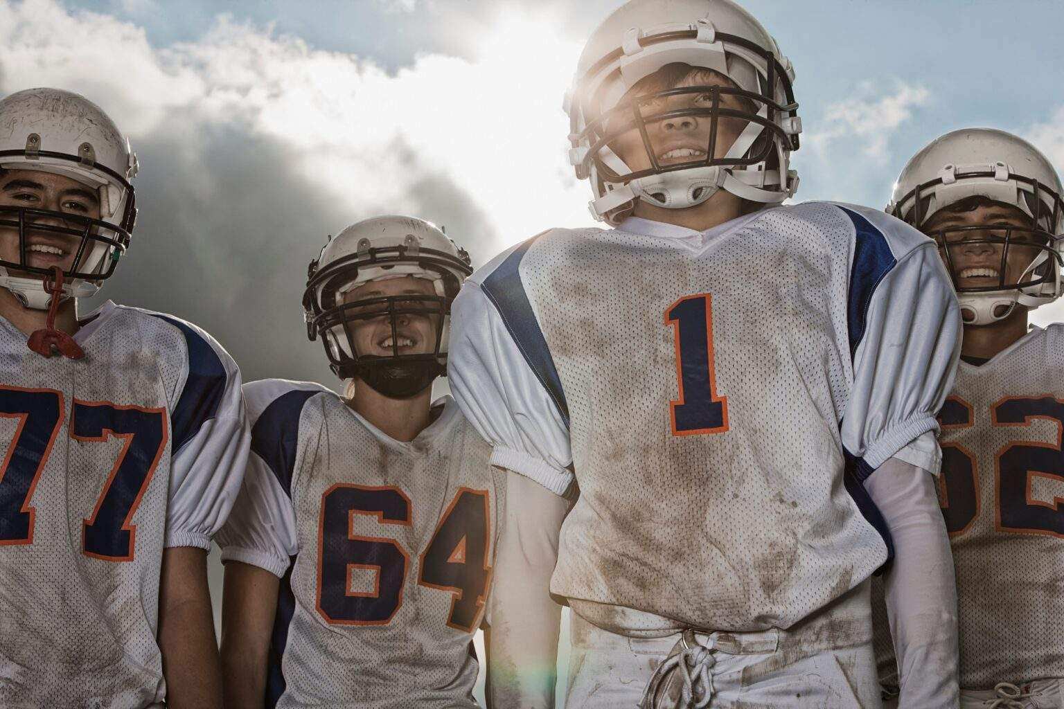 A group of football players, in uniform and helmets