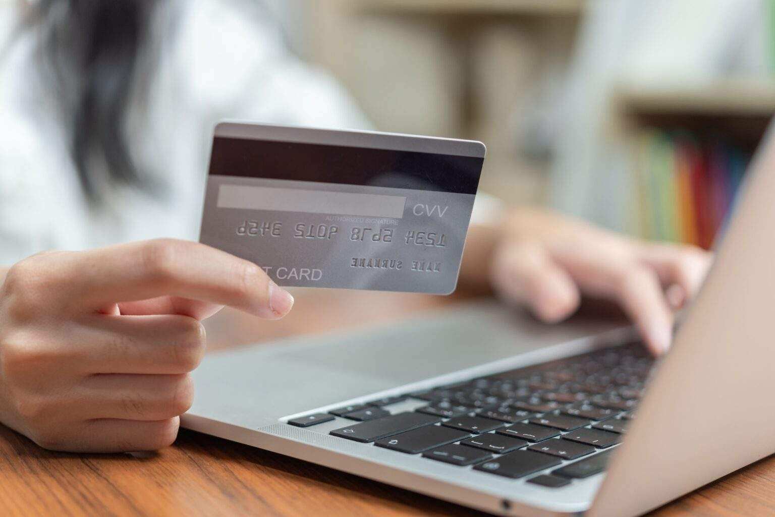 Hand holding credit card and using computer online for shopping or paying bills.