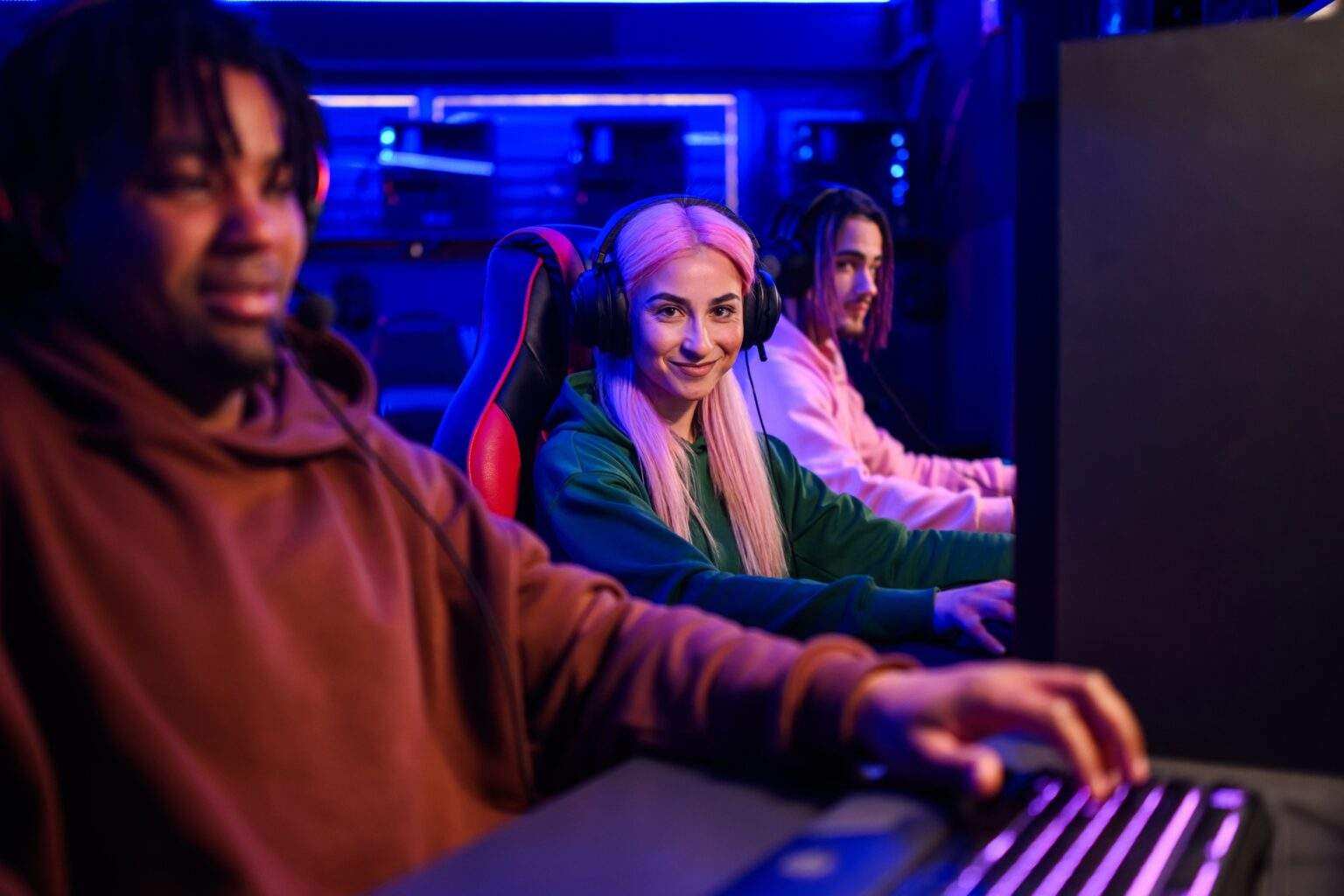 Female gamer with pink hair looking at the camera while playing a video game