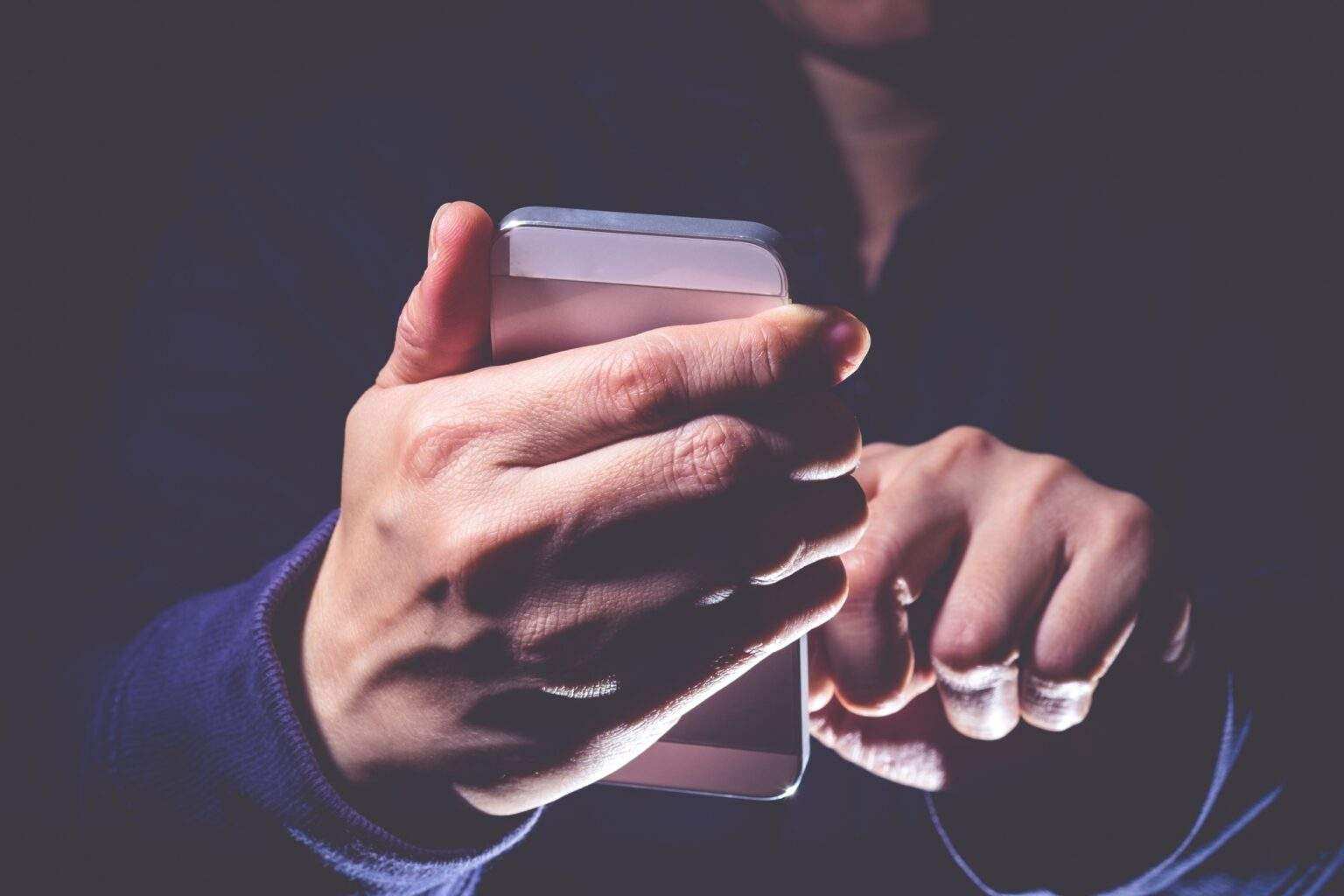 Hooded cyber crime hacker using mobile phone internet hacking