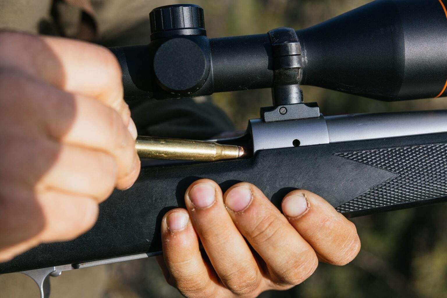 Hunter loading rifle with scope in forest