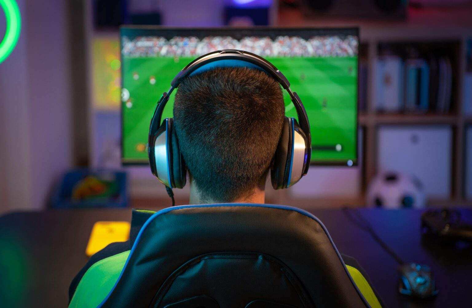 Unrecognizable young man playing sport games on computer at home.